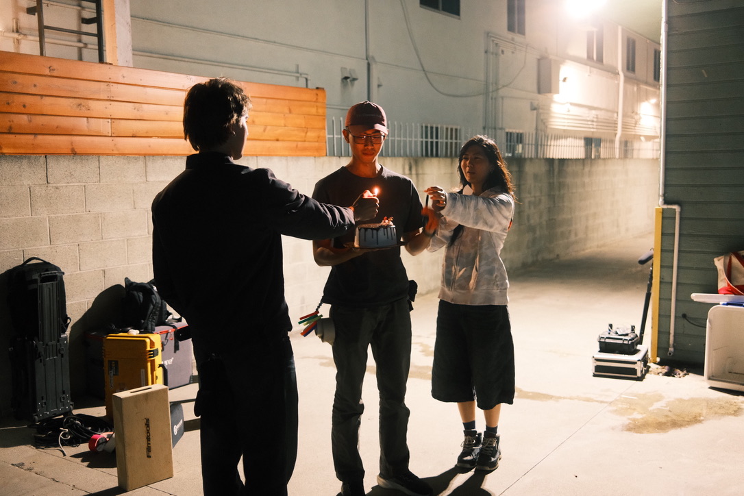 Crew lighting candles on a cake between takes