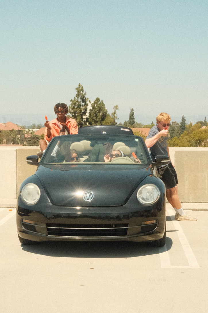 Cast gathered around a convertible on set