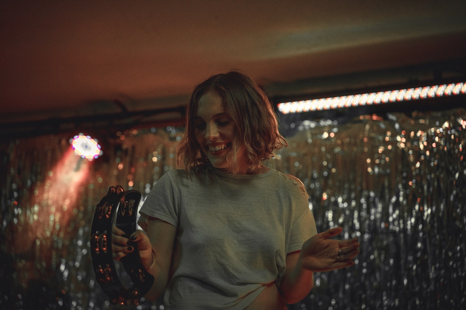 Musician smiling while playing a tambourine