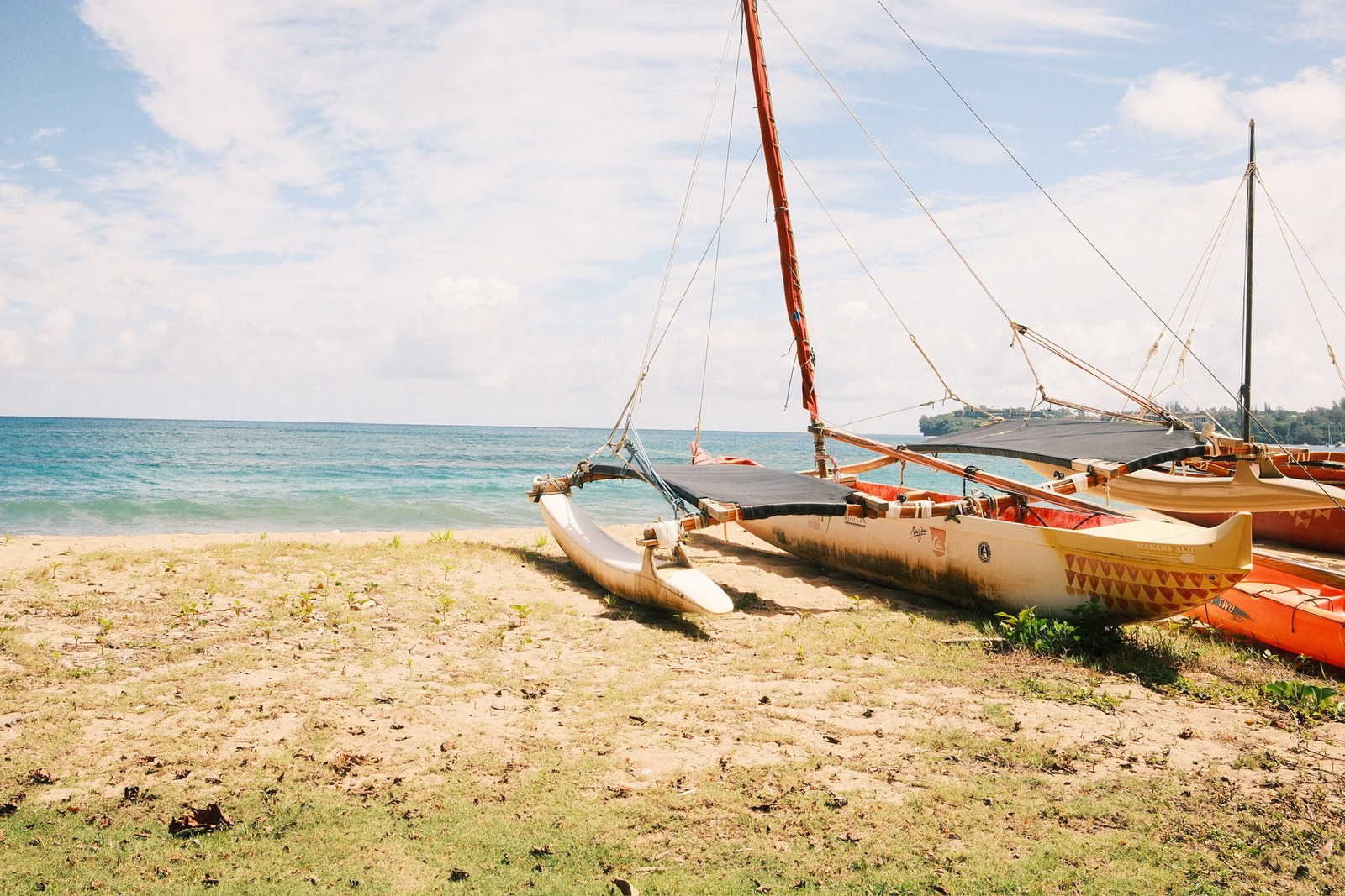 Outrigger sailing canoe resting on the sand by turquoise water