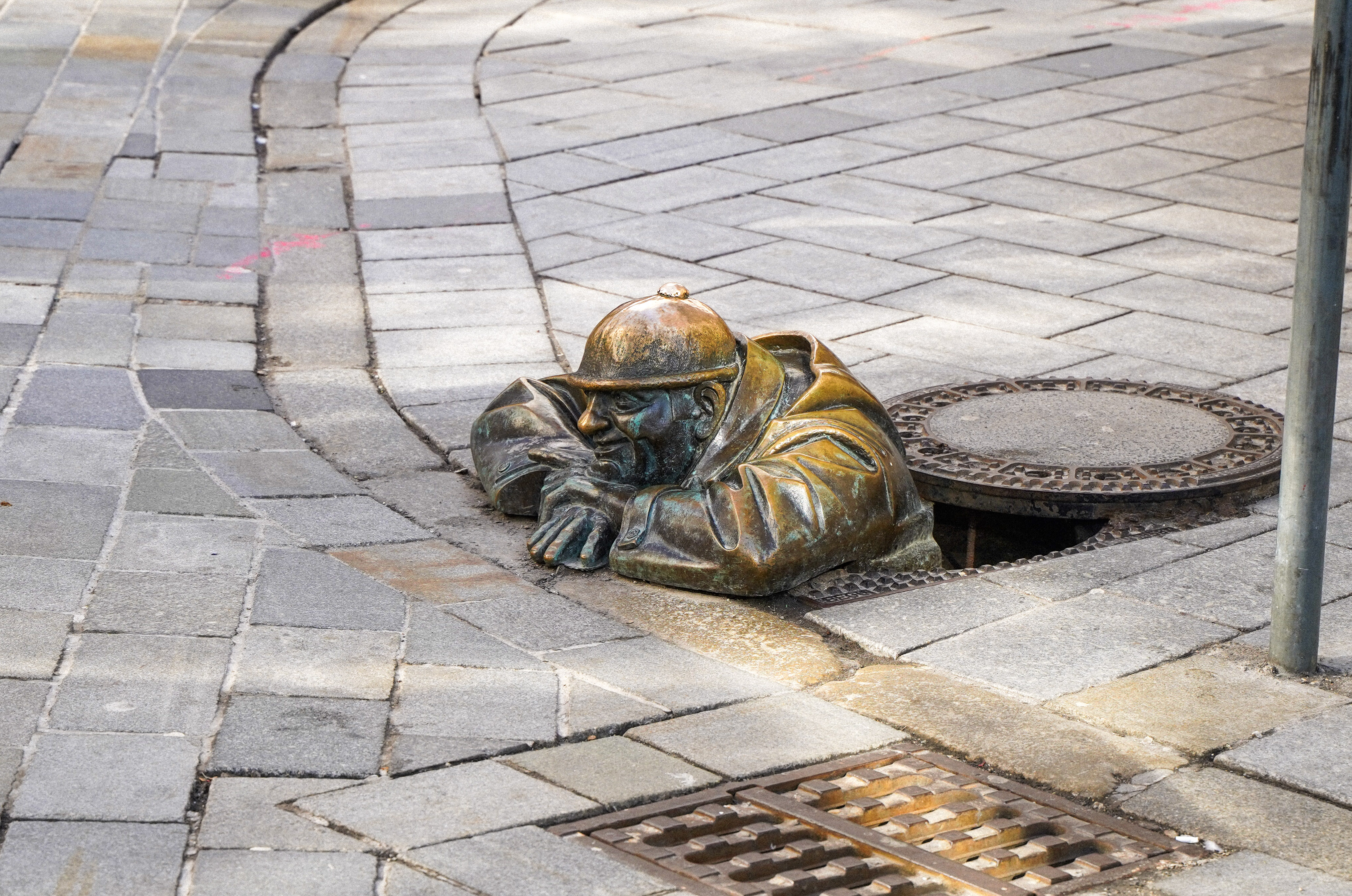 Bronze statue peeking from a manhole